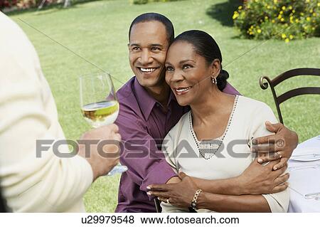 Affectionate middle aged couple sitting at outdoor table View Large Photo Image Stock Photo - Affectionate middle aged couple sitting at outdoor table. Fotosearch