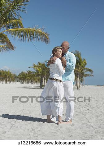 Stock Photograph - Affectionate senior couple on tropical beach. Fotosearch