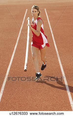 Stock Image - Athlete running with pole vault. Fotosearch