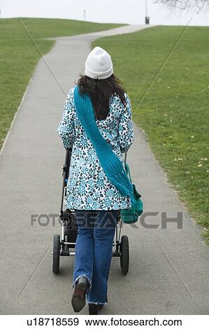 Back view of mother pushing stroller in park View Large Photo Image Stock Photo - Back view of mother pushing stroller in park. Fotosearch
