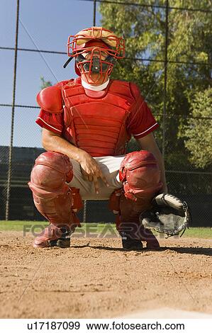 Stock Photo - Baseball catcher crouching on baseball field, giving hand signals. Fotosearch