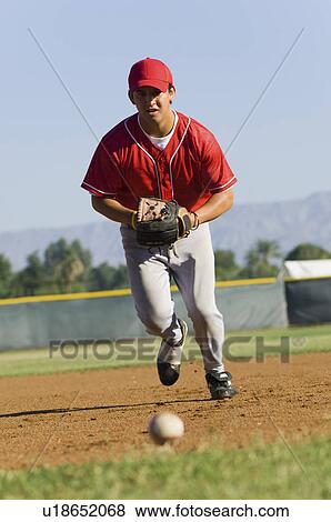 Stock Photo - Baseball fielder running towards ball on ground. Fotosearch