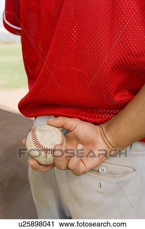 Stock Image - Baseball pitcher holding ball, (close-up), (mid section). Fotosearch