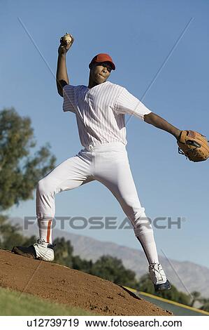Stock Photo - Baseball pitcher throwing ball during game. Fotosearch