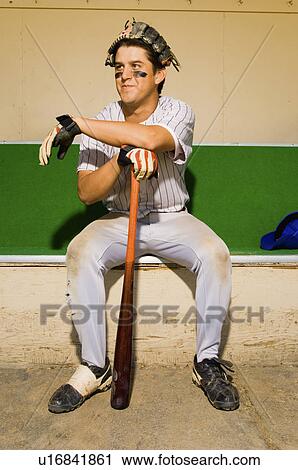 Stock Image - Baseball player sitting in dugout. Fotosearch
