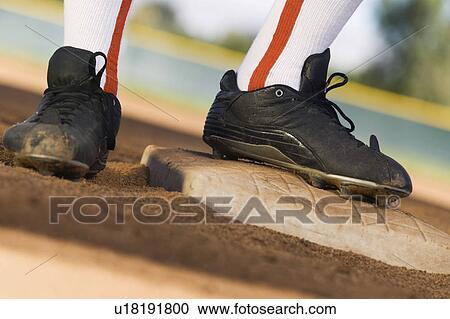 Stock Image - Baseball player standing on base, (low section). Fotosearch