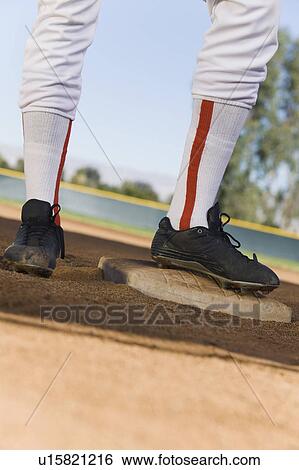 Stock Photograph - Baseball player standing on base, (low section). Fotosearch