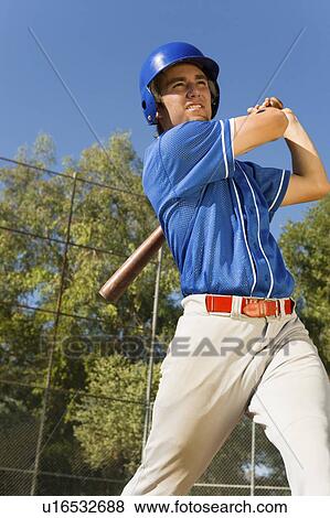 Stock Photo - Baseball player swinging baseball bat, (low angle view). Fotosearch
