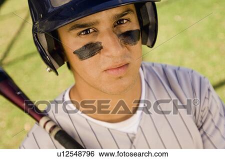 Stock Photograph - Baseball player with eye black, holding baseball bat on shoulder, (portrait), (elevated view). Fotosearch