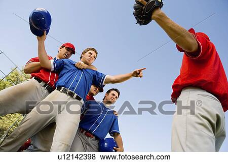 Stock Photo - Baseball players arguing on field, (low angle view). Fotosearch