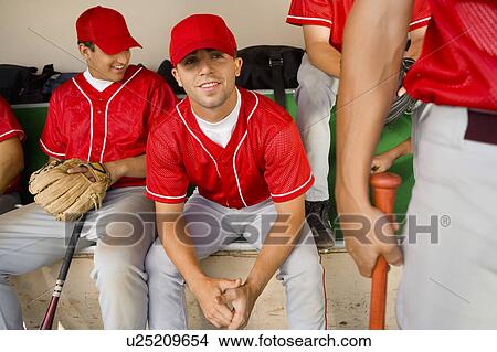 Picture - Baseball team-mates sitting in dugout. Fotosearch