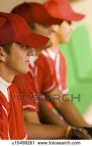 Stock Image - Baseball team-mates sitting in dugout. Fotosearch