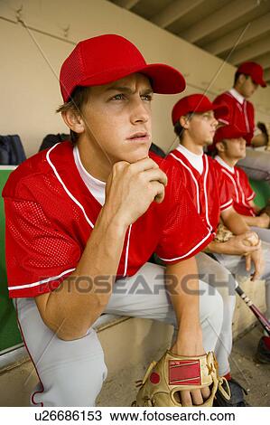 Stock Image - Baseball team-mates sitting in dugout. Fotosearch