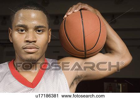 Stock Image - Basketball player holding ball, (close-up), (portrait). Fotosearch