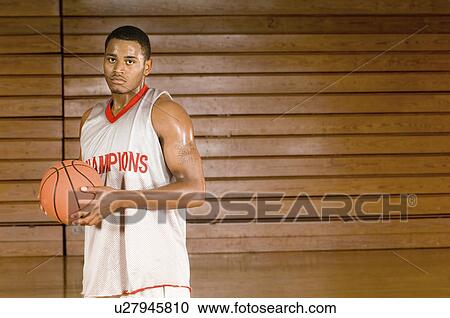 Basketball player holding ball, indoors, (portrait) View Large Photo Image Stock Image - Basketball player holding ball, indoors, (portrait). Fotosearch