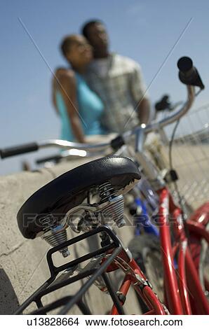 Picture - Bicycle against wall, couple in background. Fotosearch