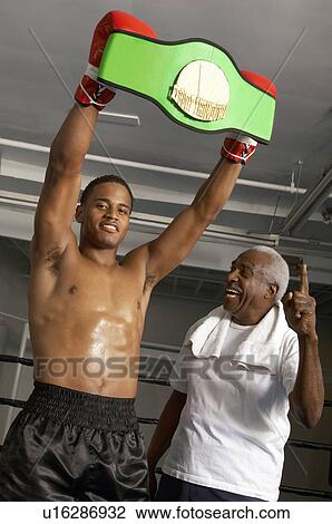 Boxer holding up champion belt with trainer View Large Photo Image Stock Image - Boxer holding up champion belt with trainer. Fotosearch