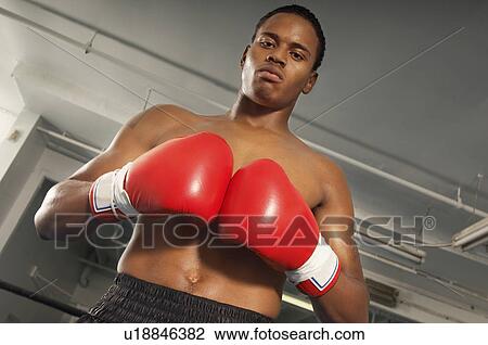 Stock Image - Boxer with red boxing gloves in gym, half length. Fotosearch