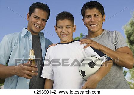 Boy (13-15) holding soccer ball, standing with two brothers, one brother holding beer bottle, front view. View Large Photo Image Stock Image - Boy (13-15) holding soccer ball, standing with two brothers, one brother holding beer bottle, front view.. Fotosearch