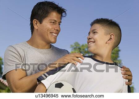 Boy (13-15) holding soccer ball, with young man View Large Photo Image Stock Photography - Boy (13-15) holding soccer ball, with young man. Fotosearch