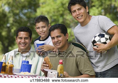 Stock Photo - Boy (13-15) with father and brothers at picnic.. Fotosearch