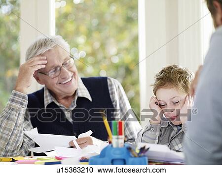 Stock Image - Boy (3-4) laughing with father and grandfather in house. Fotosearch