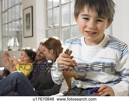 Stock Photograph - Boy (3-6) holding toy dinosaur in living room, (portrait). Fotosearch