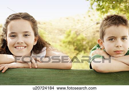 Boy (7-9) and girl (10-12) leaning against railing, portrait. View Large Photo Image Picture - Boy (7-9) and girl (10-12) leaning against railing, portrait.. Fotosearch