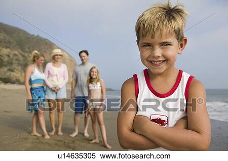 Stock Photography - Boy at Beach with His Family in Background. Fotosearch