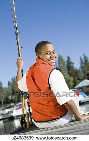Stock Photo - Boy fly fishing from pier, smiling, (portrait). Fotosearch