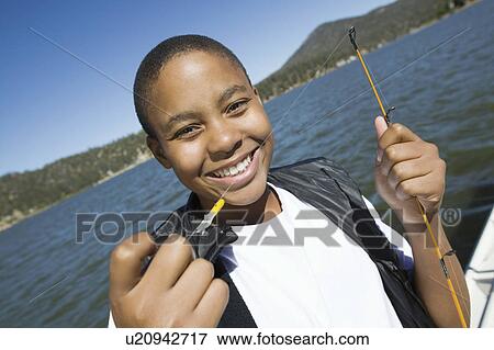 Boy fly fishing on lake, smiling, (portrait) View Large Photo Image Stock Photo - Boy fly fishing on lake, smiling, (portrait). Fotosearch