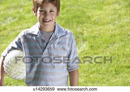 Boy holding ball in park, portrait View Large Photo Image Stock Photo - Boy holding ball in park, portrait. Fotosearch