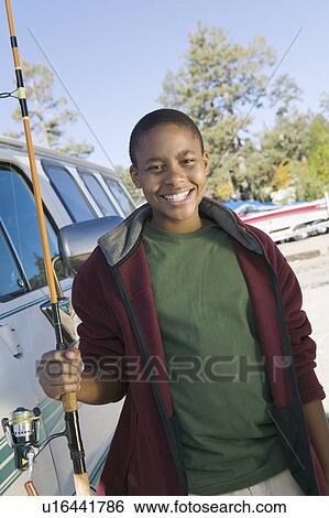 Boy holding fishing rod, smiling, (portrait) View Large Photo Image Stock Photograph - Boy holding fishing rod, smiling, (portrait). Fotosearch