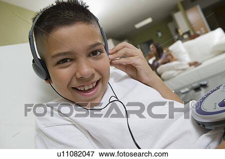 Stock Photo - Boy Listening to Music on Portable CD Player in living room, portrait, close up. Fotosearch