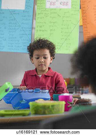 Boy looking into lunch box in classroom View Large Photo Image Stock Image - Boy looking into lunch box in classroom. Fotosearch