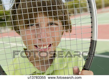 Stock Photography - Boy Looking Through Tennis Racket, portrait, close up. Fotosearch