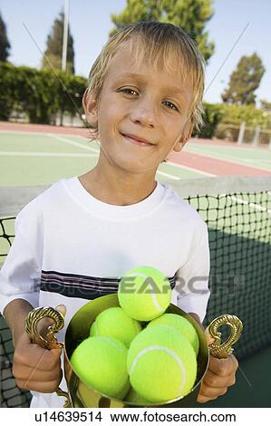 Picture - Boy on tennis court Holding Trophy Filled with tennis Balls, portrait. Fotosearch