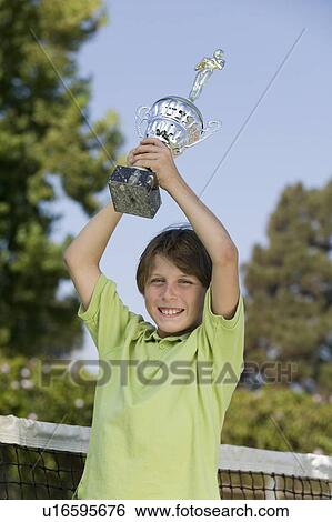 Boy on tennis court Holding up Tennis Trophy, portrait View Large Photo Image Stock Photograph - Boy on tennis court Holding up Tennis Trophy, portrait. Fotosearch