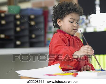 Stock Image - Boy painting in art class. Fotosearch