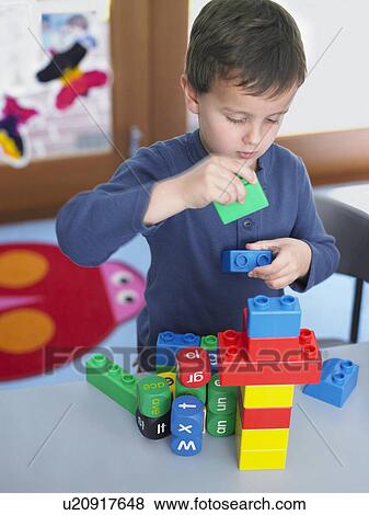 Stock Photo - Boy playing with building blocks in classroom, elevated view. Fotosearch