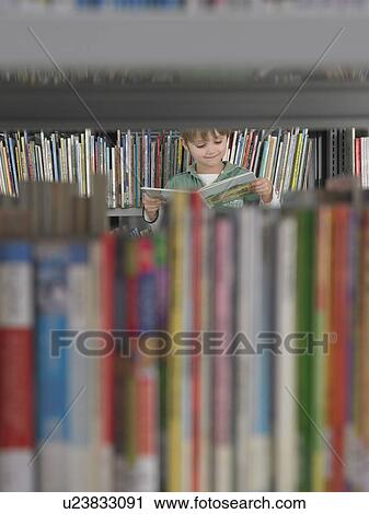 Boy reading book behind bookshelf in library View Large Photo Image Stock Image - Boy reading book behind bookshelf in library. Fotosearch