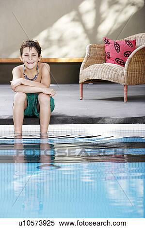 Stock Photography - Boy sitting on edge of pool, portrait. Fotosearch