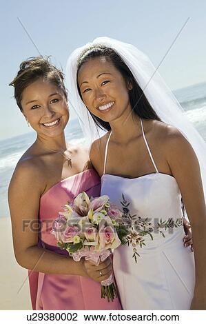 Bride and Bridesmaid smiling on beach, (portrait) View Large Photo Image Stock Image - Bride and Bridesmaid smiling on beach, (portrait). Fotosearch