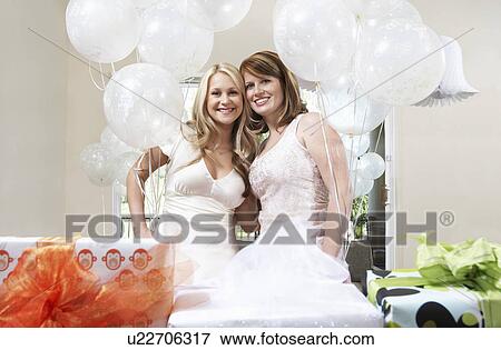 Stock Photo - Bride and Friend standing Together holding balloons at Bridal Shower. Fotosearch