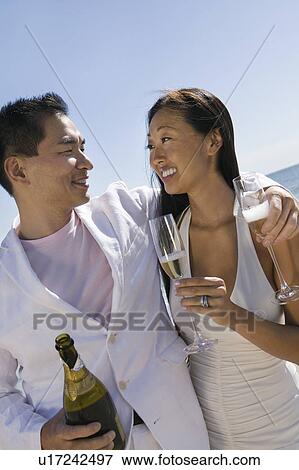 Stock Photo - Bride and Groom celebrating with champagne, outdoors. Fotosearch
