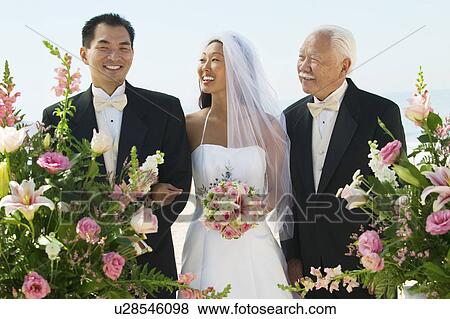 Stock Photo - Bride and groom with father, outdoors. Fotosearch