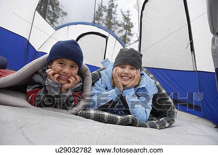 Stock Image - Brother and sister (7-12) in tent, (portrait). Fotosearch