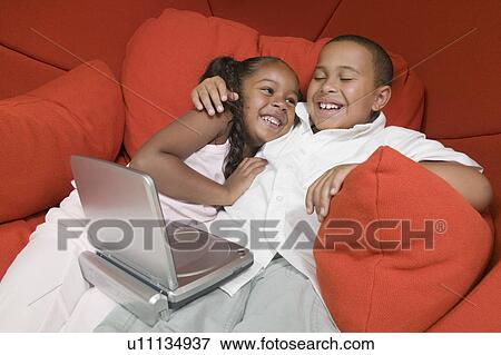 Brother and Sister on Chair watching movie on portable DVD Player, close up View Large Photo Image Stock Photo - Brother and Sister on Chair watching movie on portable DVD Player, close up. Fotosearch