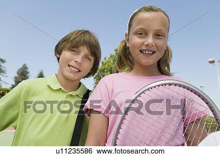Stock Photograph - Brother and Sister with Tennis Racket at tennis court, portrait, close up. Fotosearch