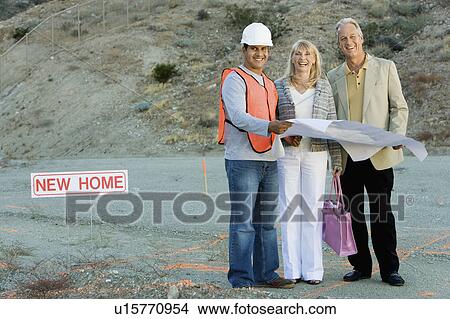 Picture - Builder and couple at new home construction site, portrait. Fotosearch